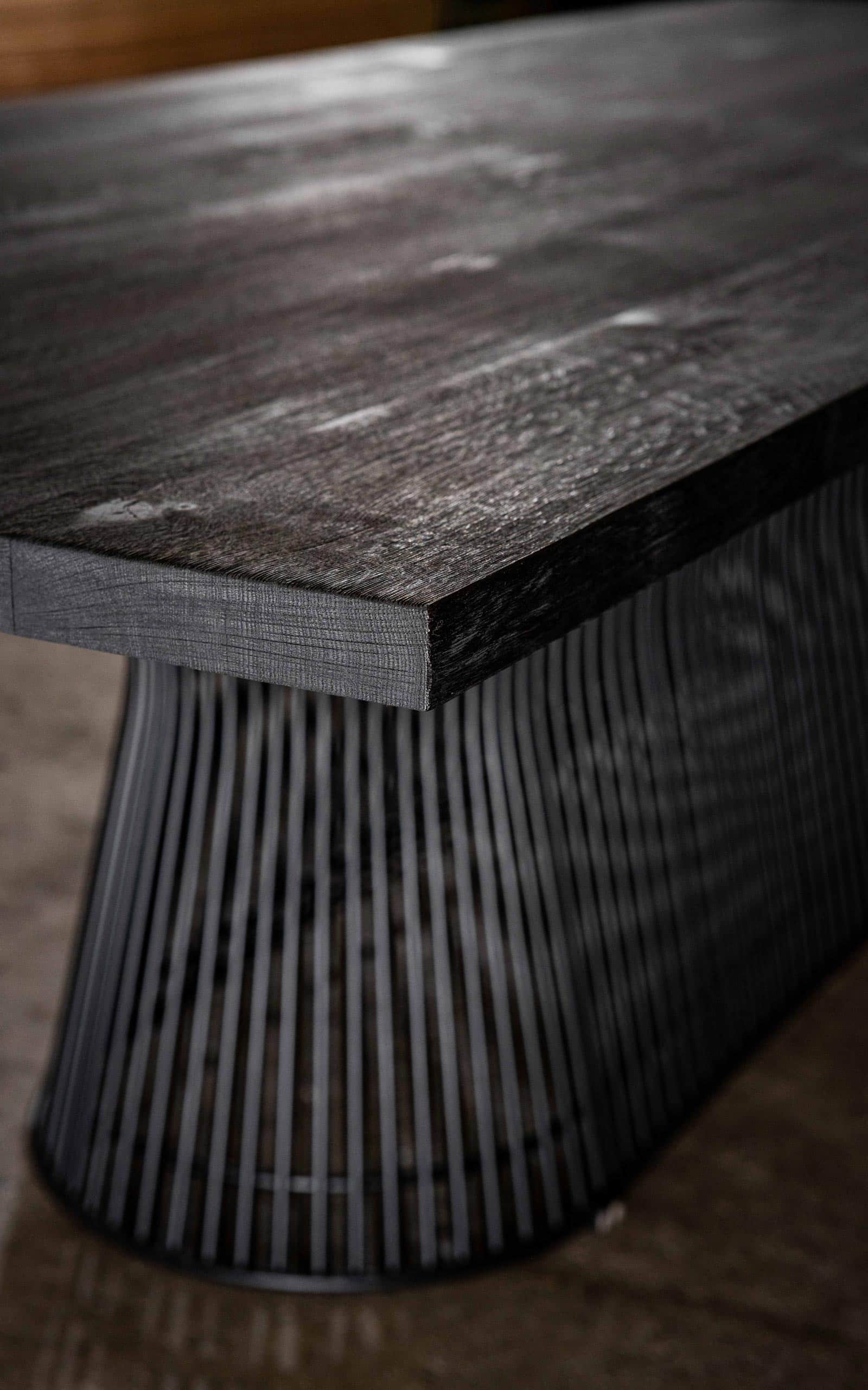 Curveo Konferenztisch mit einem schwarzen Gestell aus eng aneinandergereihten Metallstäben und einer dunklen Holz-Tischplatte.