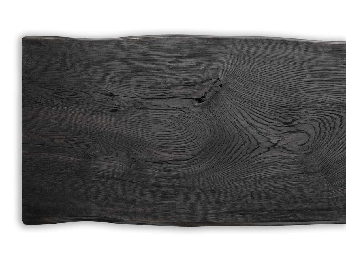 Tischplatte aus geköhlter Eiche mit kohleschwarzer Oberfläche, prägnanter Holzmaserung und natürlicher Baumkante.